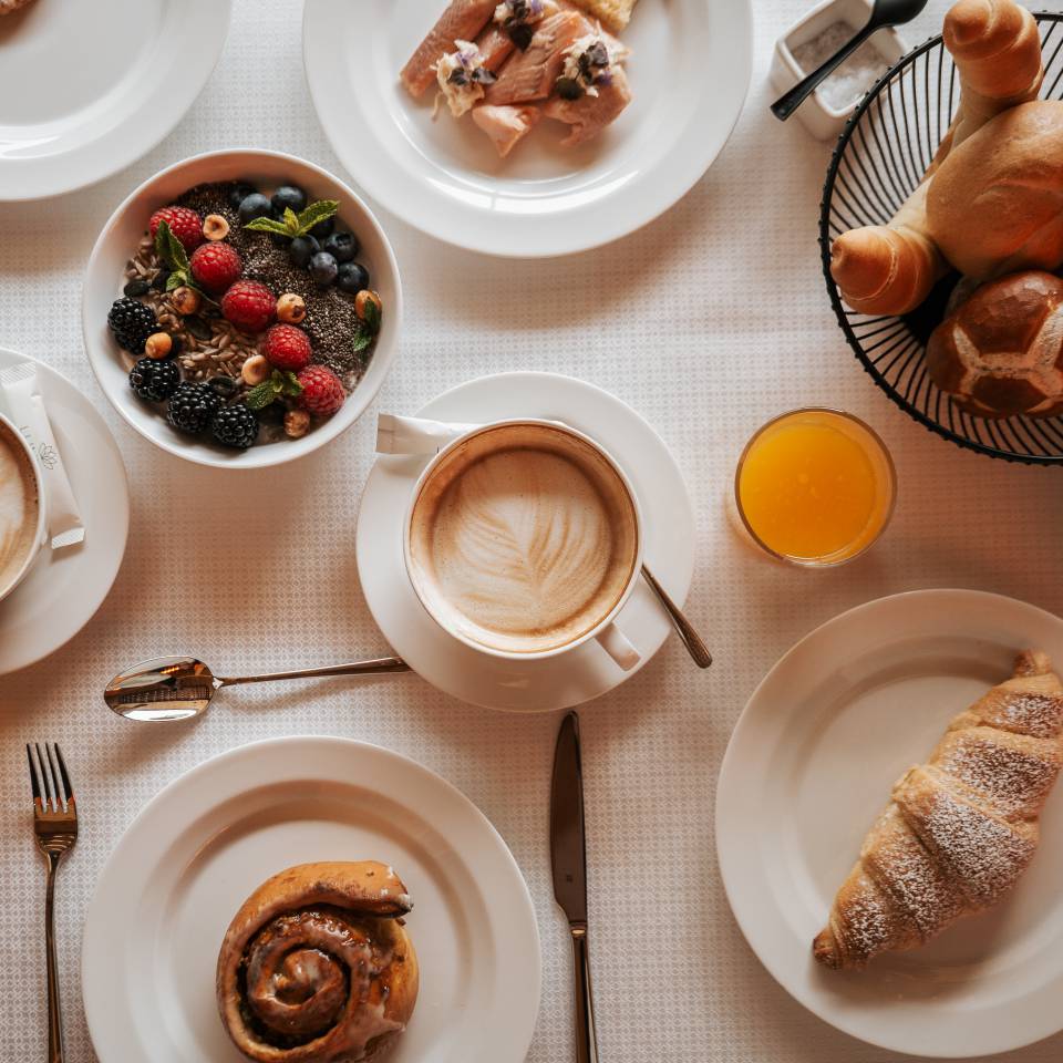 Frühstückstisch mit Capuccino, Croissant, Müsli, frische Früchten und Fruchtsaft im A&L Wellnessresort